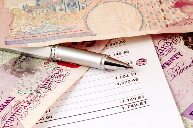 British pound bills scattered on desk with billing sheet