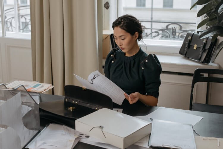 A female-presenting lawyer reviewing legal malpractice claim do،ents at a desk in an office