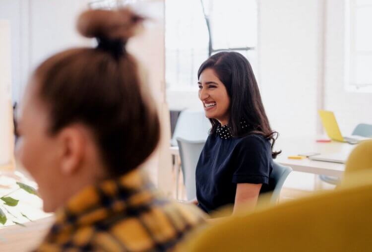 Photo of a woman laughing at work with another smiling coworker out of focus