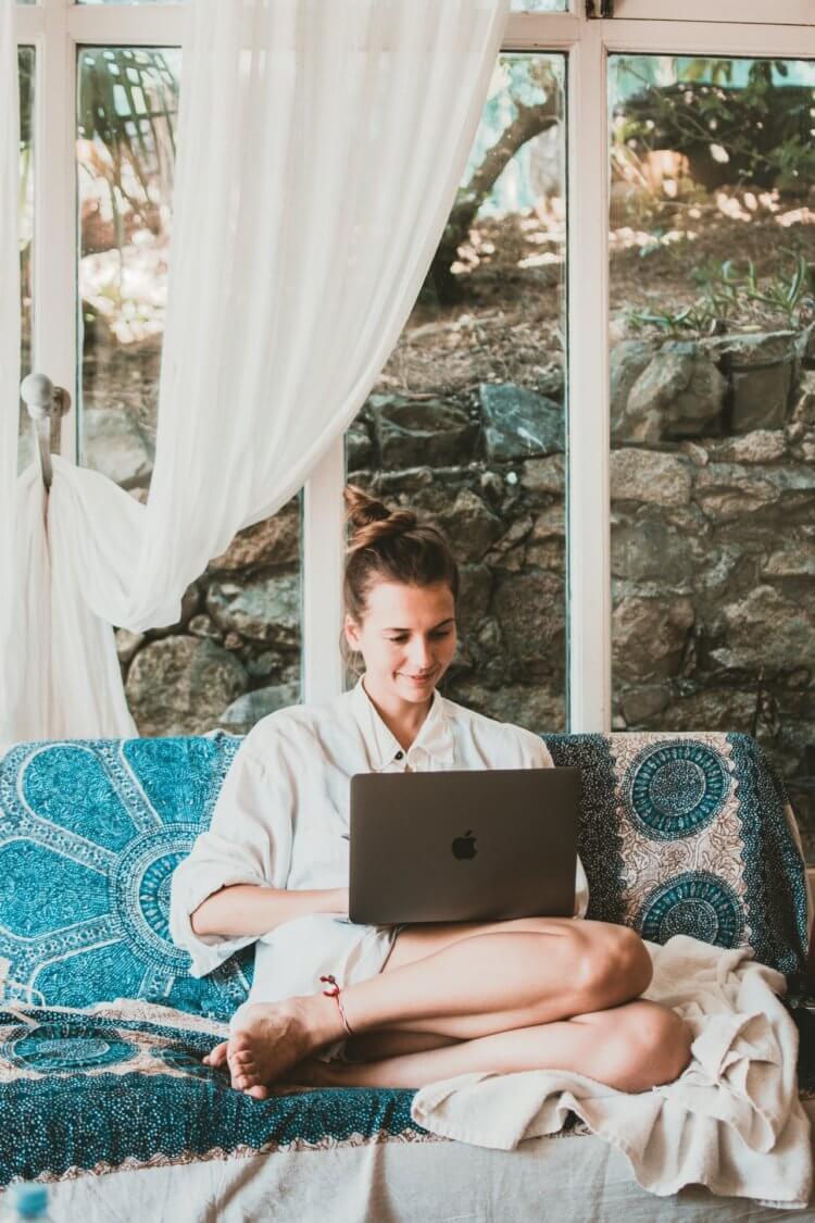 woman working on laptop while sitting on a couch in a cozy cabin