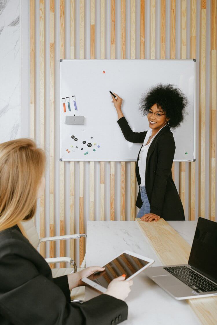 woman leading a team meeting in front of a white board