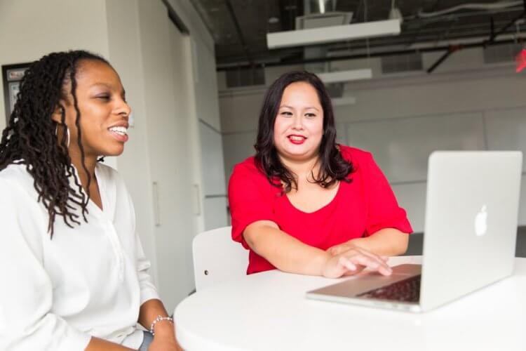 two women chatting near a laptop