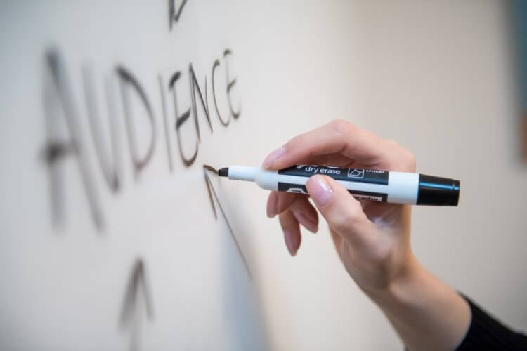 Person writing the word "audience" on a whiteboard