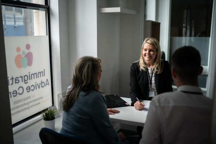 A photo of a lawyer working with two clients at a table in an office.