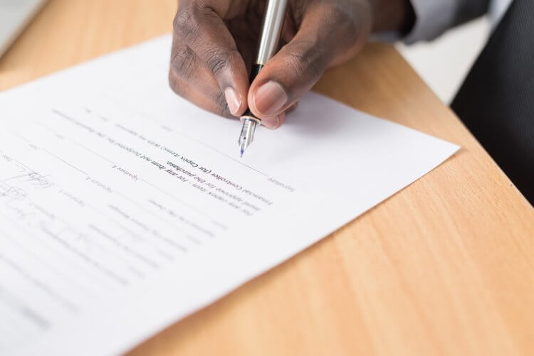 Photo of a person's hand writing on a legal document