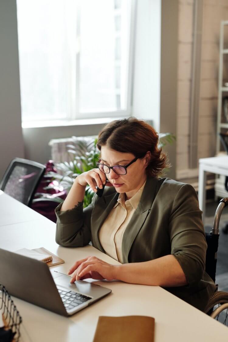 A photo of a female presenting lawyer on the phone while using a laptop to research the best payment processor for their law firm
