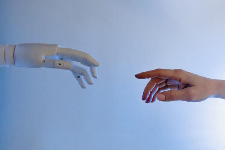 شخصی دراز می کند تا دست ربات را لمس کند
