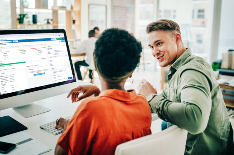 A photo of two lawyers sitting at a desk in front of a computer using legal matter management software