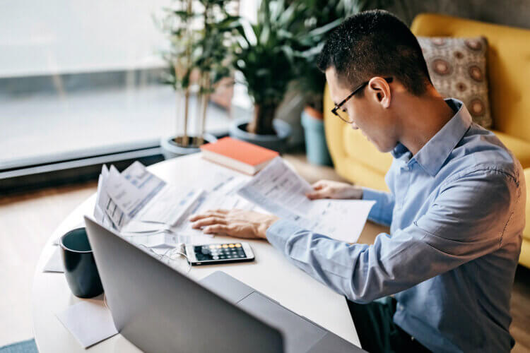 A photo of someone calculating numbers at a desk in order to determine the FDIC insurance limit for trust accounts