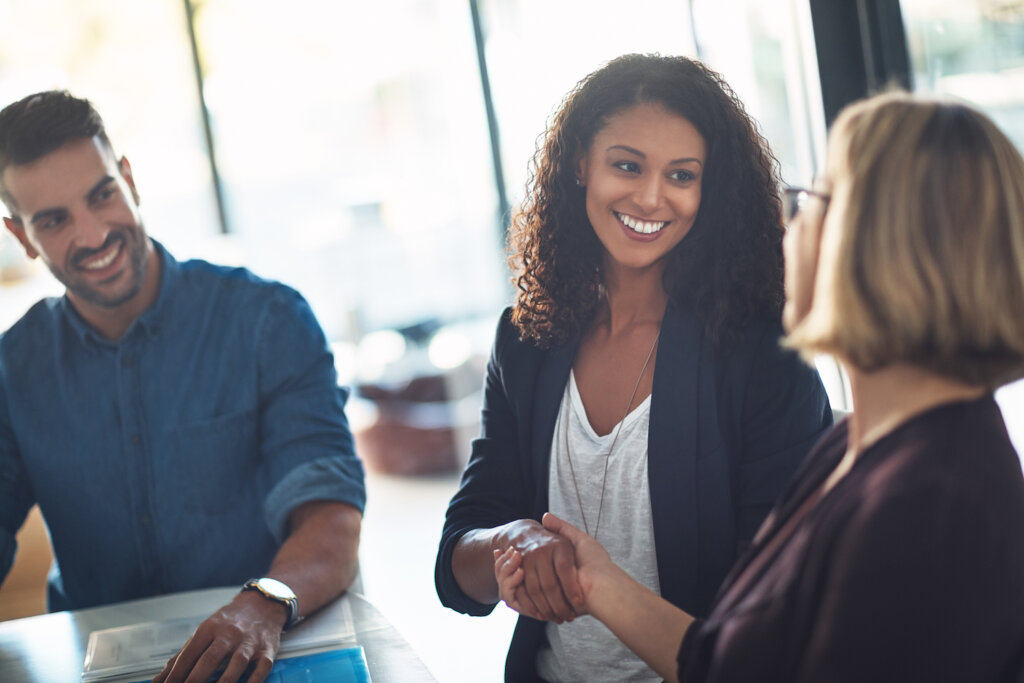 A photo of three people standing, two of which are shaking hands. They appear to be lawyers at an event celebrating International Be Kind to Lawyers Day