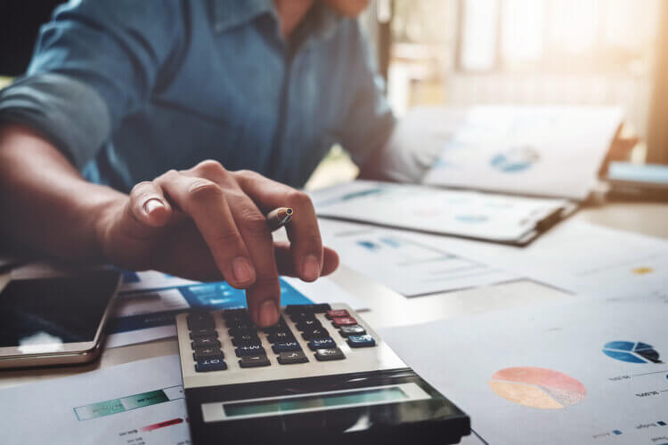 A photo of a lawyer sitting at a desk using a calculator for their general ledger.