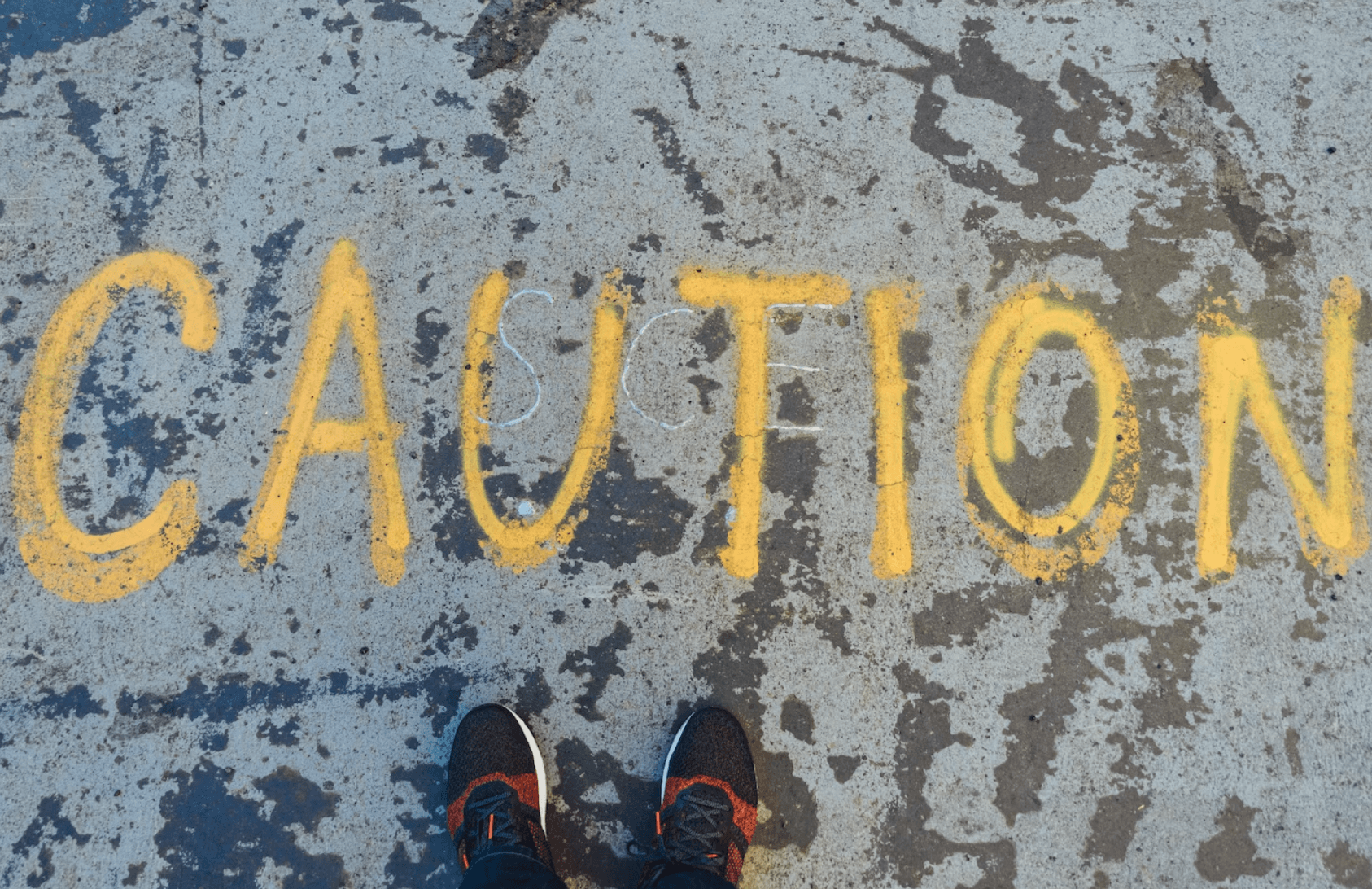 A person standing in front of the words caution written on the ground