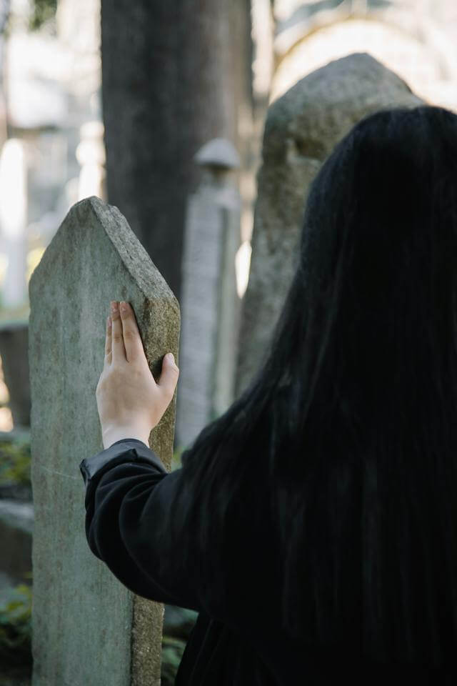 A woman touching a gravestone.