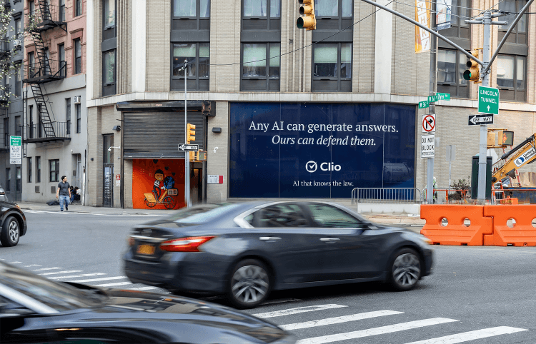 Outdoor billboard on a city building reads: Any AI can generate answers. Ours can defend them. Clio. AI that knows the law.